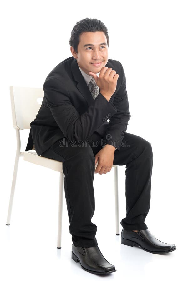 Uomo d'affari asiatico dell'ente completo che si siede sulla sedia bianca e sul pensiero fotografia stock Uomo d'affari asiatico dell'ente completo che si siede sulla sedia bianca e sul pensiero fotografia stock