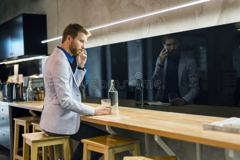 Uomo d'affari bello che beve e che per mezzo del telefono immagini stock Uomo d'affari bello che beve e che per mezzo del telefono immagini stock