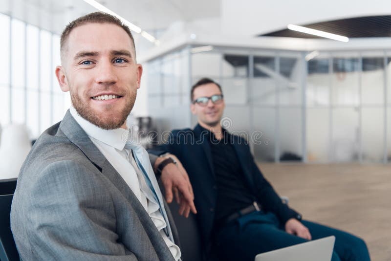 Uomo d'affari bello con il collega su fondo all'aeroporto fotografia stock libera da diritti Uomo d'affari bello con il collega su fondo all'aeroporto fotografia stock libera da diritti