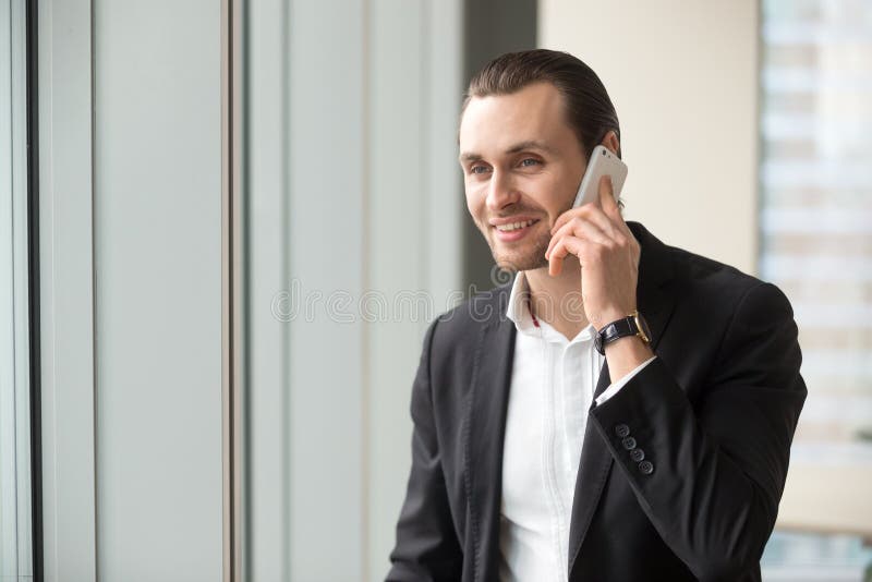 Uomo d'affari bello sorridente in vestito che parla sul cellulare immagini stock libere da diritti Uomo d'affari bello sorridente in vestito che parla sul cellulare immagini stock libere da diritti