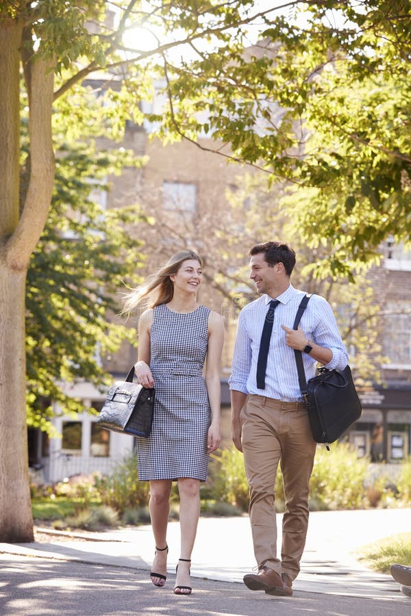 Uomo d'affari And Businesswoman Walk da lavorare attraverso il parco della città fotografia stock Uomo d'affari And Businesswoman Walk da lavorare attraverso il parco della città fotografia stock