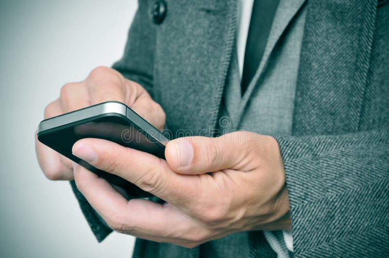 Uomo d'affari con cappotto che usa uno smartphone fotografia stock