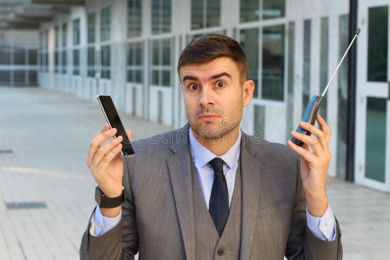 Uomo d'affari che confronta nuovo e vecchio telefono fotografie stock libere da diritti Uomo d'affari che confronta nuovo e vecchio telefono fotografie stock libere da diritti