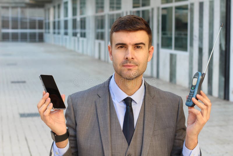 Uomo d'affari che confronta nuovo e vecchio telefono immagine stock libera da diritti Uomo d'affari che confronta nuovo e vecchio telefono immagine stock libera da diritti