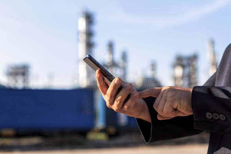 Uomo d'affari che controlla intorno alla pianta della raffineria di petrolio con il chiaro cielo fotografia stock Uomo d'affari che controlla intorno alla pianta della raffineria di petrolio con il chiaro cielo fotografia stock