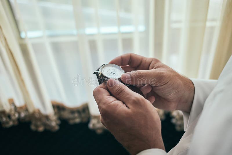 Uomo d'affari che controlla tempo sul suo orologio, uomo che mette orologio a disposizione, sposo che si prepara di mattina prima fotografie stock libere da diritti Uomo d'affari che controlla tempo sul suo orologio, uomo che mette orologio a disposizione, sposo che si prepara di mattina prima fotografie stock libere da diritti