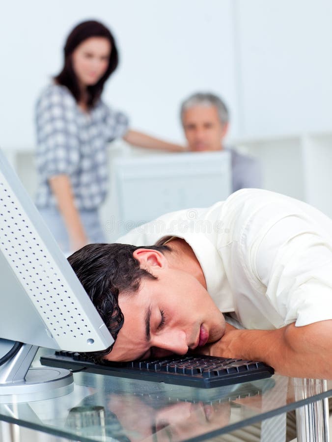 Businessman sleeping on his keyboard while colleagues watching him in the background. Businessman sleeping on his keyboard while colleagues watching him in the background