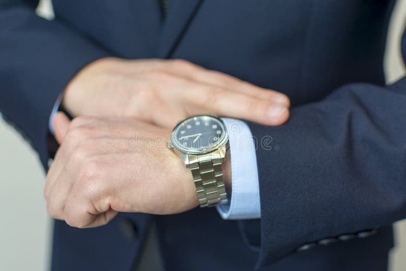 Uomo d'affari che esamina il suo orologio sulla sua mano immagine stock libera da diritti Uomo d'affari che esamina il suo orologio sulla sua mano immagine stock libera da diritti