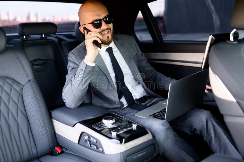 Uomo d'affari che lavora sul portatile in un sedile posteriore della macchina esecutiva Concetto di lavoro, successo, viaggiare
