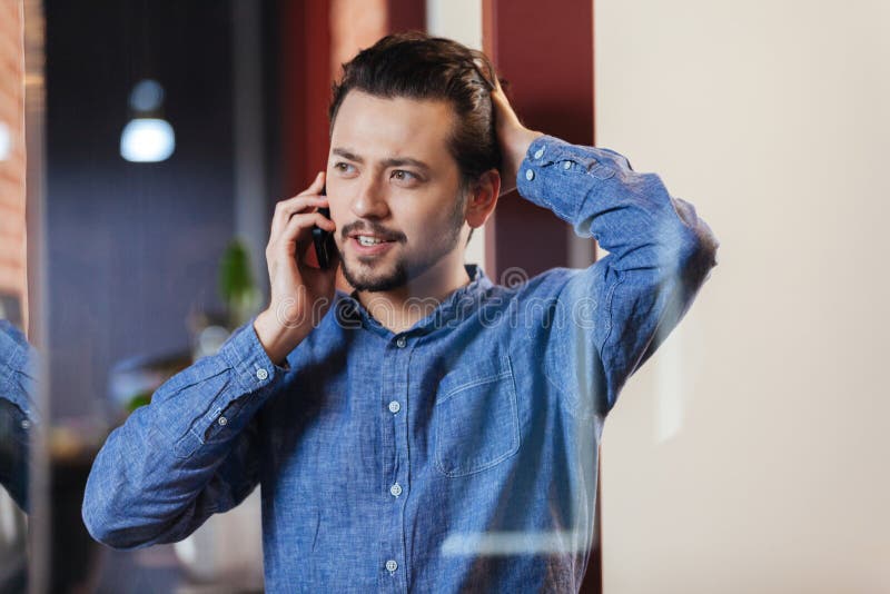 Uomo d'affari che parla sul telefono in ufficio fotografia stock Uomo d'affari che parla sul telefono in ufficio fotografia stock