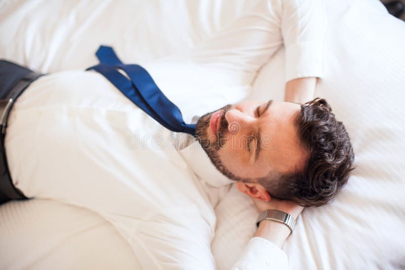 Uomo d'affari che si rilassa su un letto fotografia stock Uomo d'affari che si rilassa su un letto fotografia stock