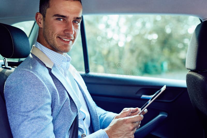 Uomo d'affari che si siede in un'automobile con il computer della compressa