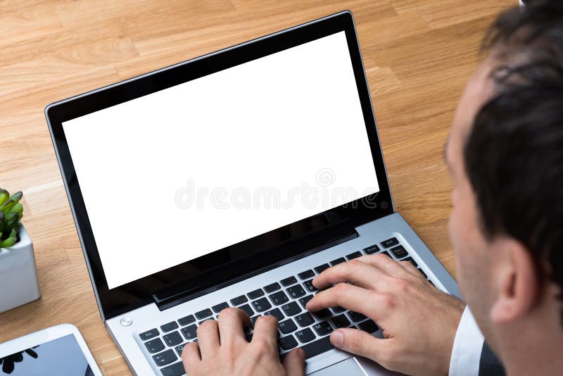 Uomo d'affari che utilizza un laptop con schermo vuoto sulla scrivania immagini stock