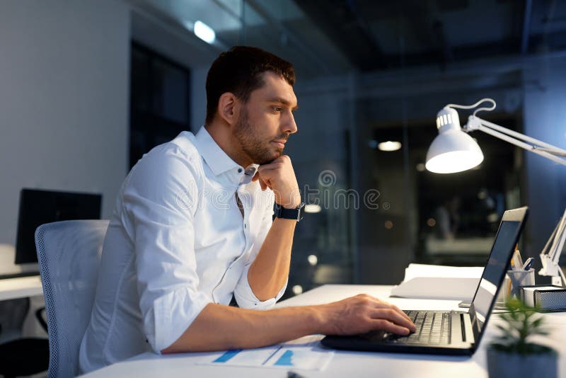 Uomo d'affari con funzionamento del computer portatile all'ufficio di notte immagini stock libere da diritti Uomo d'affari con funzionamento del computer portatile all'ufficio di notte immagini stock libere da diritti