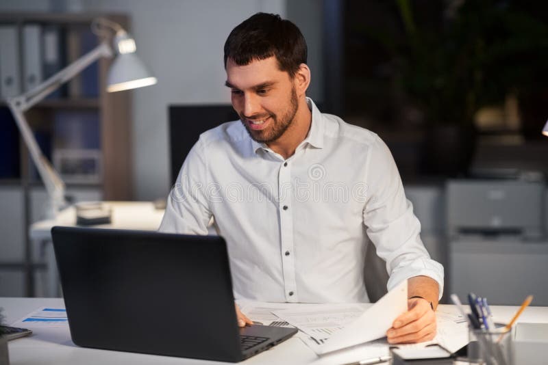 Uomo d'affari con funzionamento del computer portatile all'ufficio di notte immagine stock libera da diritti Uomo d'affari con funzionamento del computer portatile all'ufficio di notte immagine stock libera da diritti