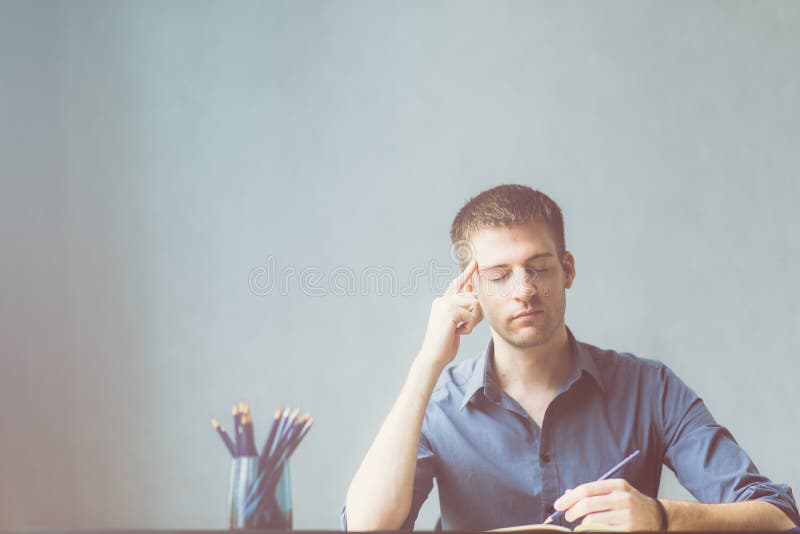 Uomo d'affari dei Caucasians che porta una camicia blu agitata all'ufficio del lavoro Emicrania nella pianificazione affare di cr fotografia stock Uomo d'affari dei Caucasians che porta una camicia blu agitata all'ufficio del lavoro Emicrania nella pianificazione affare di cr fotografia stock