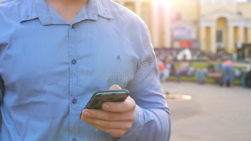 Uomo d'affari di successo in camicia in mezzo alla strada della città e con smartphone. persona sicura che scrive un messaggio o