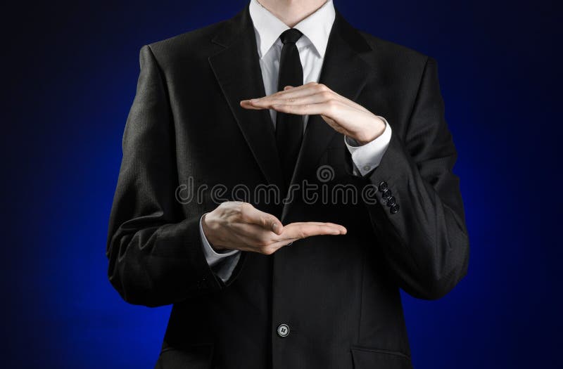 Uomo d'affari ed argomento di gesto: un uomo in un vestito nero ed in una camicia bianca che mostrano i gesti con le mani su un f immagini stock libere da diritti Uomo d'affari ed argomento di gesto: un uomo in un vestito nero ed in una camicia bianca che mostrano i gesti con le mani su un f immagini stock libere da diritti