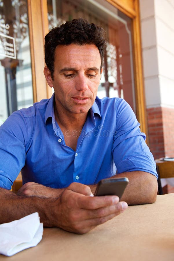 Uomo d'affari facendo uso del telefono cellulare al caffè all'aperto fotografie stock Uomo d'affari facendo uso del telefono cellulare al caffè all'aperto fotografie stock