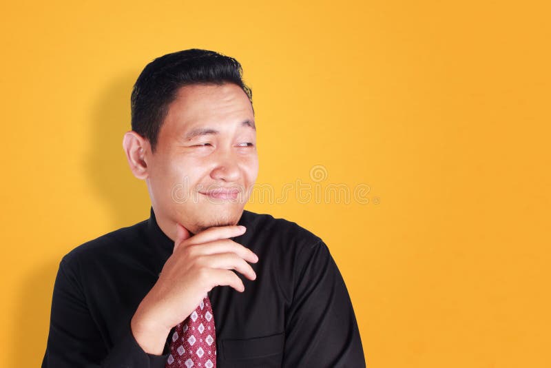 Uomo d'affari felice sopra fondo arancio. Ritratto del gesto sorridente felice del giovane uomo d'affari asiatico attraente, sopra il fondo arancio della parete