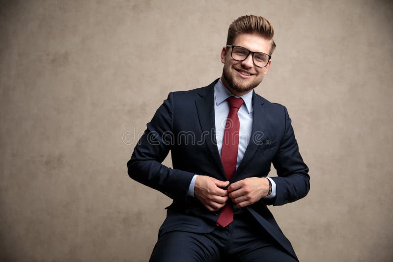 Uomo d'affari positivo che regola il suoi rivestimento e risata fotografia stock Uomo d'affari positivo che regola il suoi rivestimento e risata fotografia stock