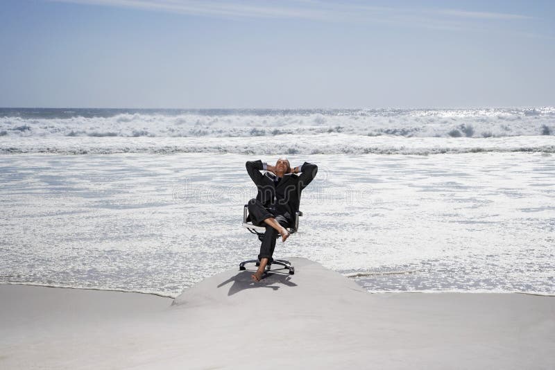 Uomo d'affari Relaxing On Chair alla spiaggia