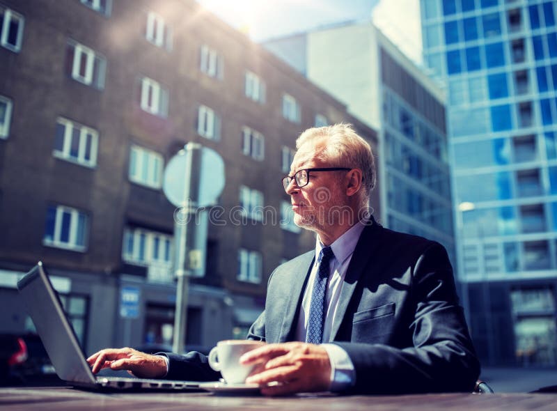Uomo d'affari senior con il caff? bevente del computer portatile immagine stock Uomo d'affari senior con il caff? bevente del computer portatile immagine stock