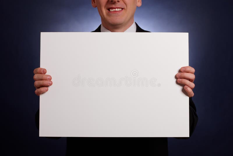 Uomo d'affari sorridente che tiene una grande scheda in bianco fotografie stock libere da diritti Uomo d'affari sorridente che tiene una grande scheda in bianco fotografie stock libere da diritti
