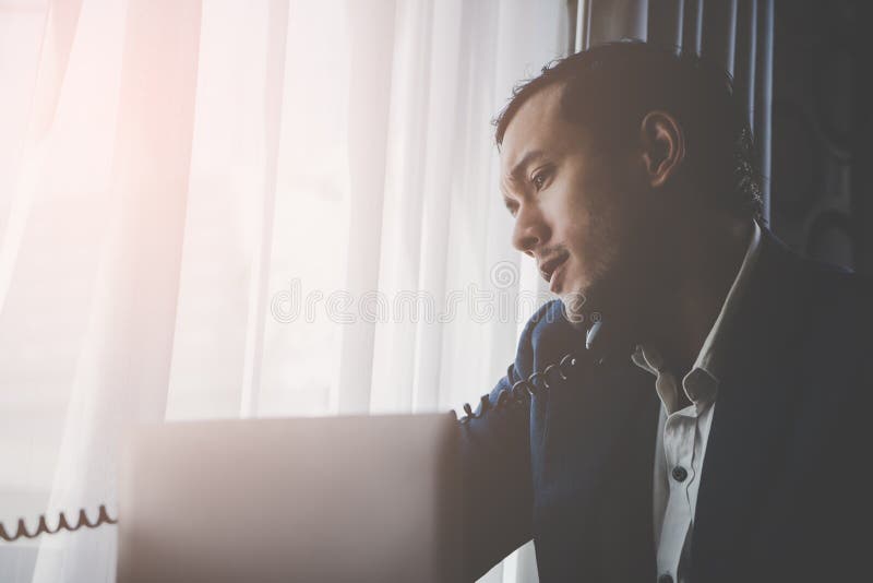 Uomo di affari che fa chiamata dentro sulla vecchia linea terrestre del telefono di modo immagine stock libera da diritti Uomo di affari che fa chiamata dentro sulla vecchia linea terrestre del telefono di modo immagine stock libera da diritti