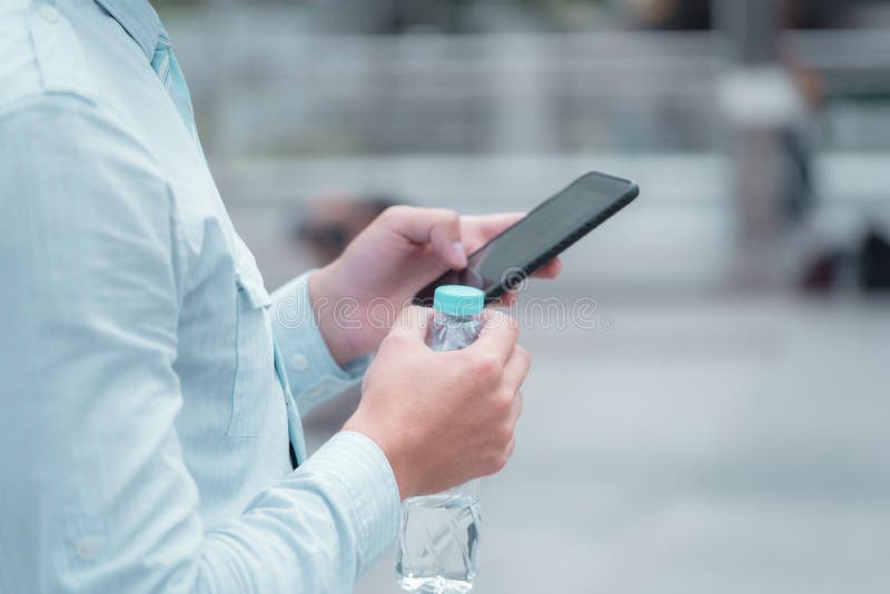 Uomo di affari che prende un'acqua potabile della rottura e che usando fon mobile immagini stock libere da diritti Uomo di affari che prende un'acqua potabile della rottura e che usando fon mobile immagini stock libere da diritti