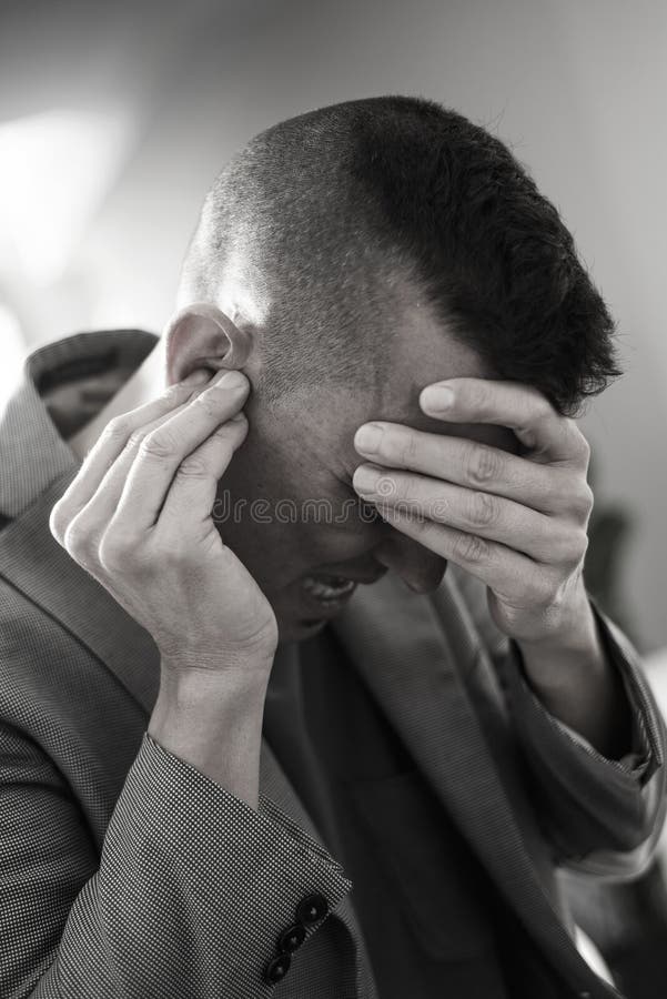 Uomo di sofferenza con le sue mani in sua testa immagine stock Uomo di sofferenza con le sue mani in sua testa immagine stock