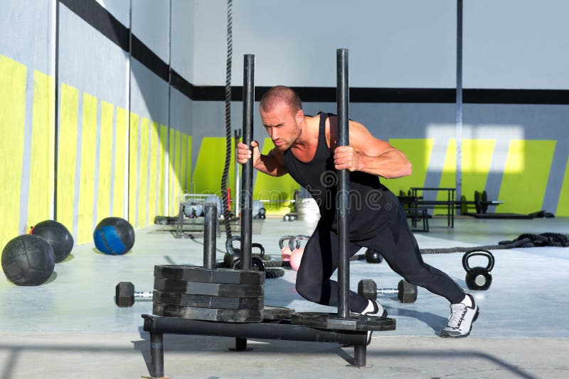 Uomo di spinta della slitta di Crossfit che spinge allenamento dei pesi fotografia stock Uomo di spinta della slitta di Crossfit che spinge allenamento dei pesi fotografia stock