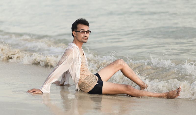 Uomo di vita seduto sulla spiaggia e che guarda la telecamera fotografie stock