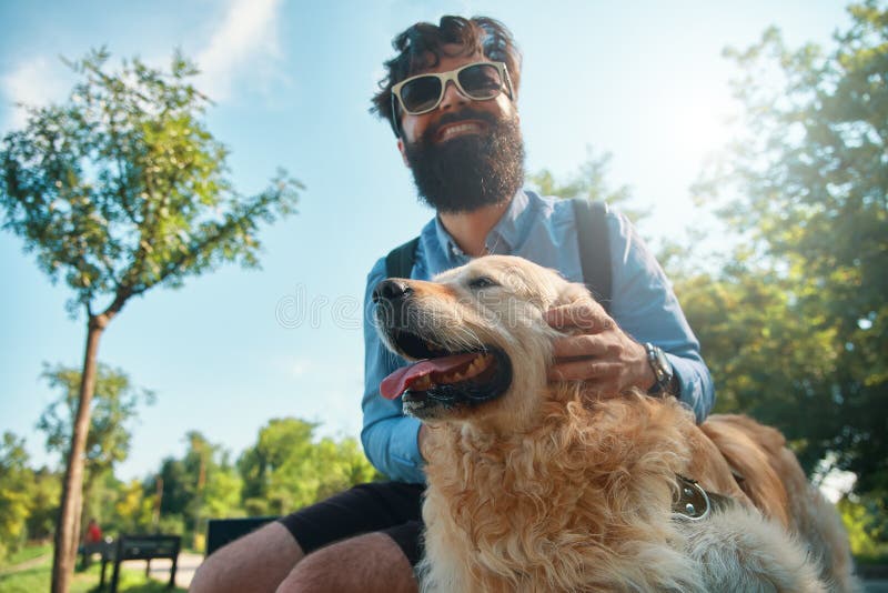 Uomo e cane divertendosi, giocare, facente i fronti divertenti mentre restin fotografie stock Uomo e cane divertendosi, giocare, facente i fronti divertenti mentre restin fotografie stock