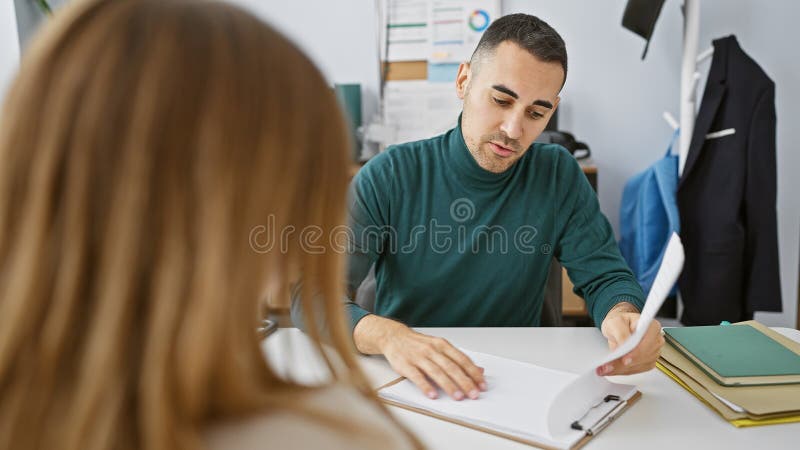 Uomo e donna che collaborano in un ufficio e rivedono insieme documenti che raffigurano un ambiente professionale di lavoro immagine stock