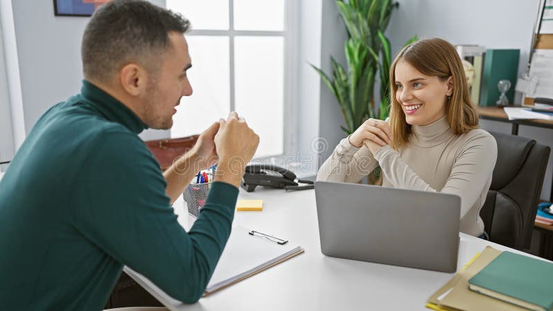 Uomo e donna che lavorano insieme in un ufficio moderno con computer portatili e oggetti di cancelleria che riflettono il lavoro d immagini stock