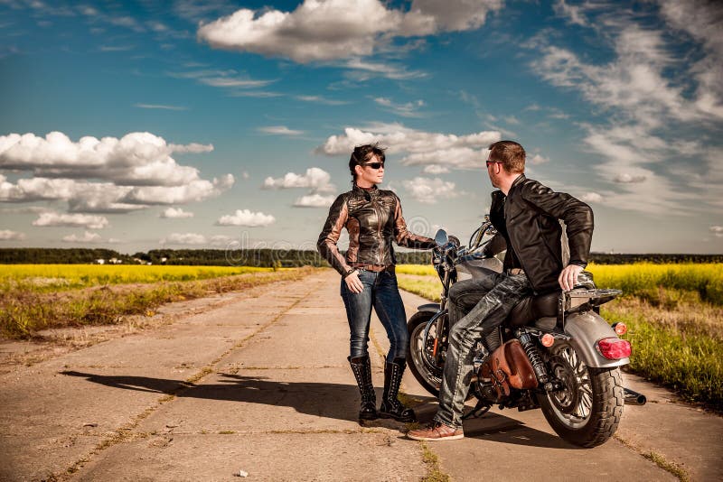 Uomo e donna delle coppie dei motociclisti vicino ad un motociclo sulla strada fotografia stock libera da diritti Uomo e donna delle coppie dei motociclisti vicino ad un motociclo sulla strada fotografia stock libera da diritti