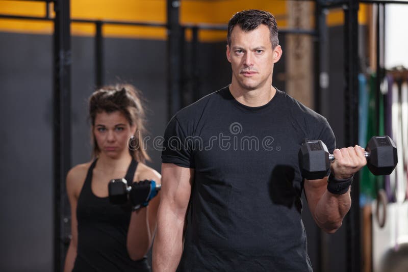 Uomo e donna di addestramento del bilanciere in una palestra fotografie stock libere da diritti Uomo e donna di addestramento del bilanciere in una palestra fotografie stock libere da diritti