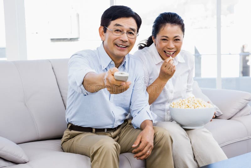 Uomo e donna sorridenti che si siedono sullo strato fotografie stock libere da diritti Uomo e donna sorridenti che si siedono sullo strato fotografie stock libere da diritti