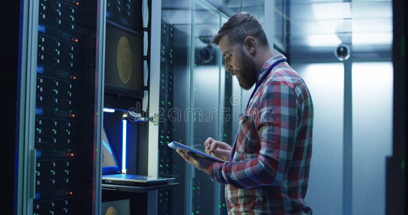 Uomo facendo uso del computer portatile sull'azienda agricola estraente nel centro dati immagini stock libere da diritti