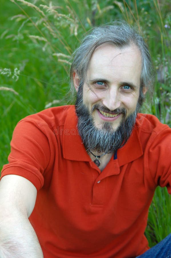 Uomo felice barbuto che si siede in un fondo verde il giorno soleggiato, potrait immagini stock libere da diritti Uomo felice barbuto che si siede in un fondo verde il giorno soleggiato, potrait immagini stock libere da diritti