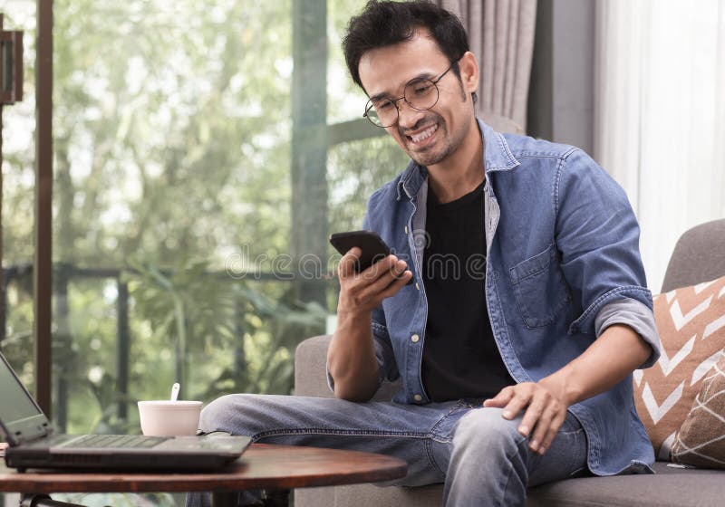Uomo felice che usa smartphone mentre è seduto a casa o al bar fotografia stock libera da diritti