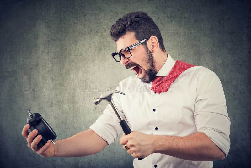 Uomo frustrato di affari pronto a rompere una sveglia con il martello immagine stock libera da diritti Uomo frustrato di affari pronto a rompere una sveglia con il martello immagine stock libera da diritti