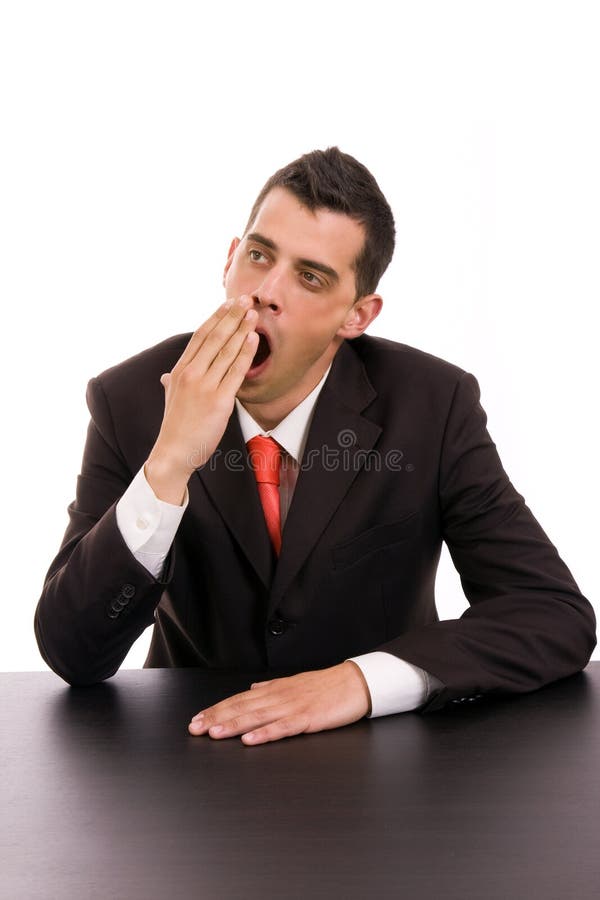 Yawning young business man on the desk, isolated on white background. Yawning young business man on the desk, isolated on white background