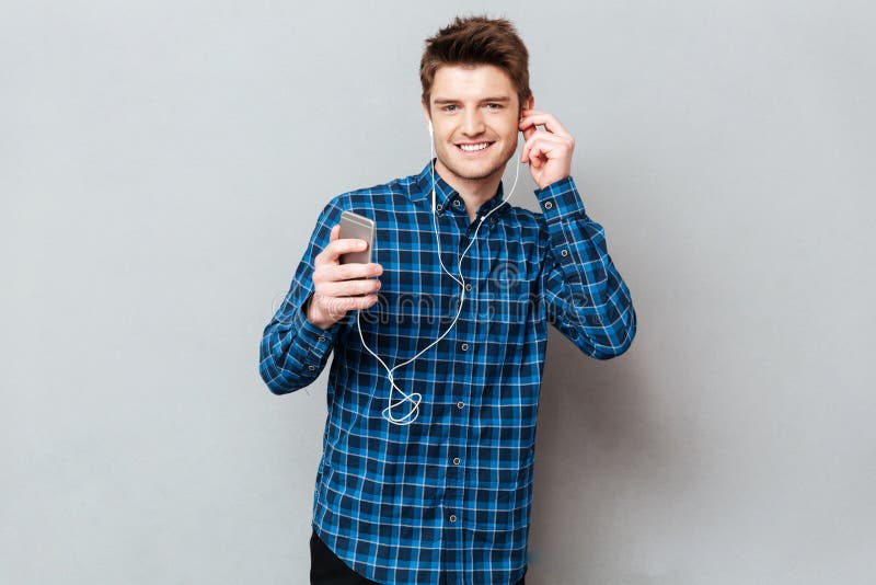 Uomo grazioso che guarda macchina fotografica mentre musica d'ascolto fotografia stock libera da diritti Uomo grazioso che guarda macchina fotografica mentre musica d'ascolto fotografia stock libera da diritti