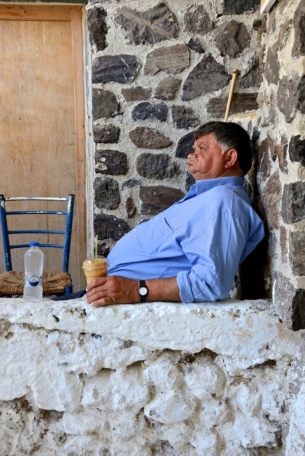 Uomo greco anziano che si siede fuori della sua casa, caffè bevente immagini stock Uomo greco anziano che si siede fuori della sua casa, caffè bevente immagini stock