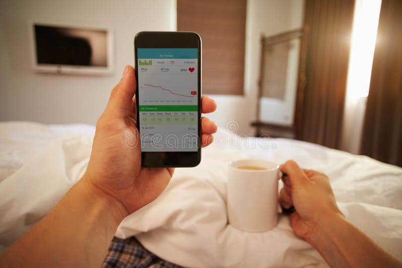 Uomo a letto che esamina salute che controlla App sul telefono cellulare