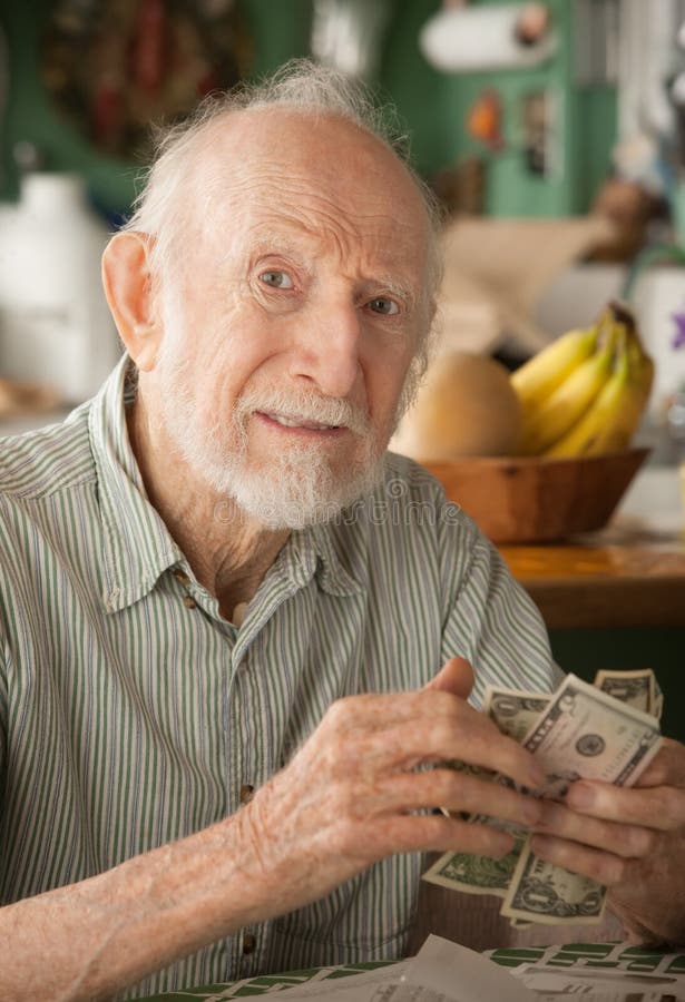 Senior man at home with a few dollars counting his money. Senior man at home with a few dollars counting his money