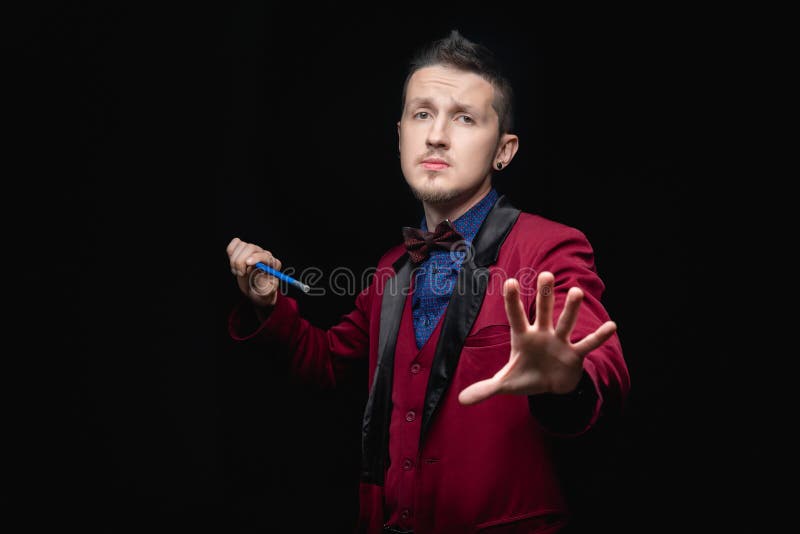 Uomo mago con la bacchetta magica sullo sfondo nero fotografia stock libera da diritti