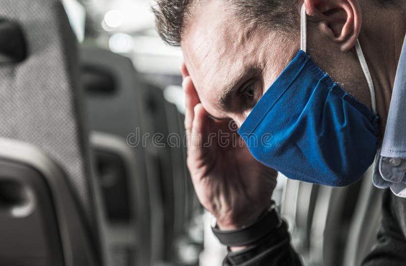 Uomo in maschera blu siede in ansia nei trasporti pubblici in tempi incerti immagine stock